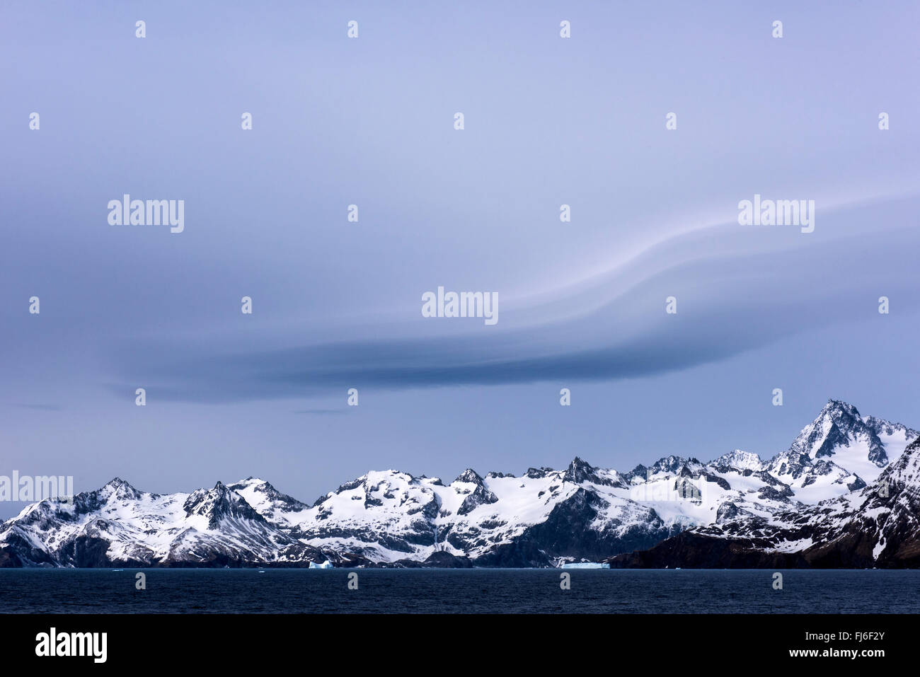 Nuvole lenticolare (Altocumulus lenticularis) sulle montagne innevate Gold Harbour, Georgia del Sud Foto Stock