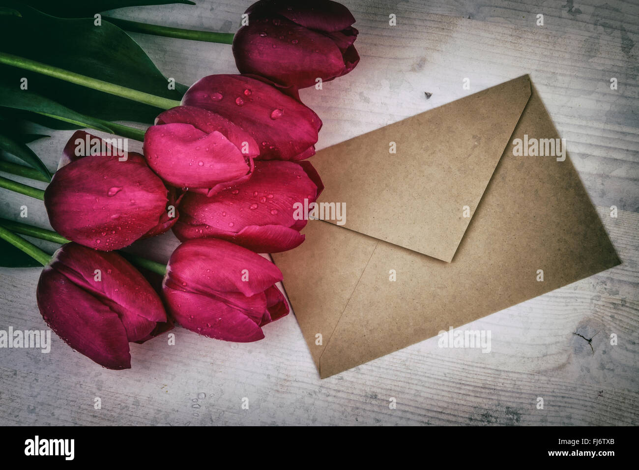 Vintage vita ancora con tulipani rossi e busta di carta Foto Stock