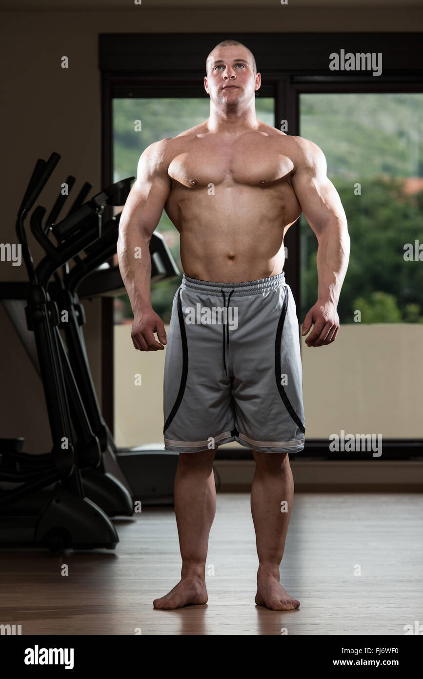 Ritratto di un giovane uomo che pongono il Bodybuilding pone nel moderno Centro Fitness Foto Stock