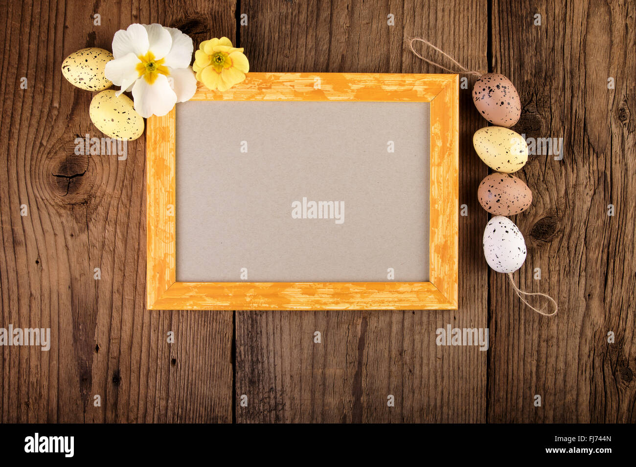 La pasqua con decor di color pastello di uova e il giallo il telaio in legno. Vista da sopra con copia spazio. Foto Stock