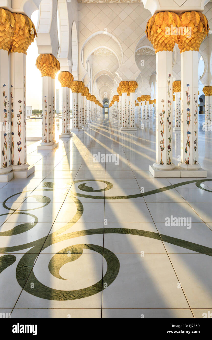 Raggi di sole passando attraverso il pilastro a corridoi della Moschea Sheikh Zayed, Abu Dhabi. Foto Stock