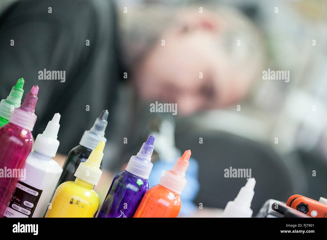 Bottiglie di inchiostro e tattoo artist inchiostrazione un client con un bio-meccanica tattoo Foto Stock