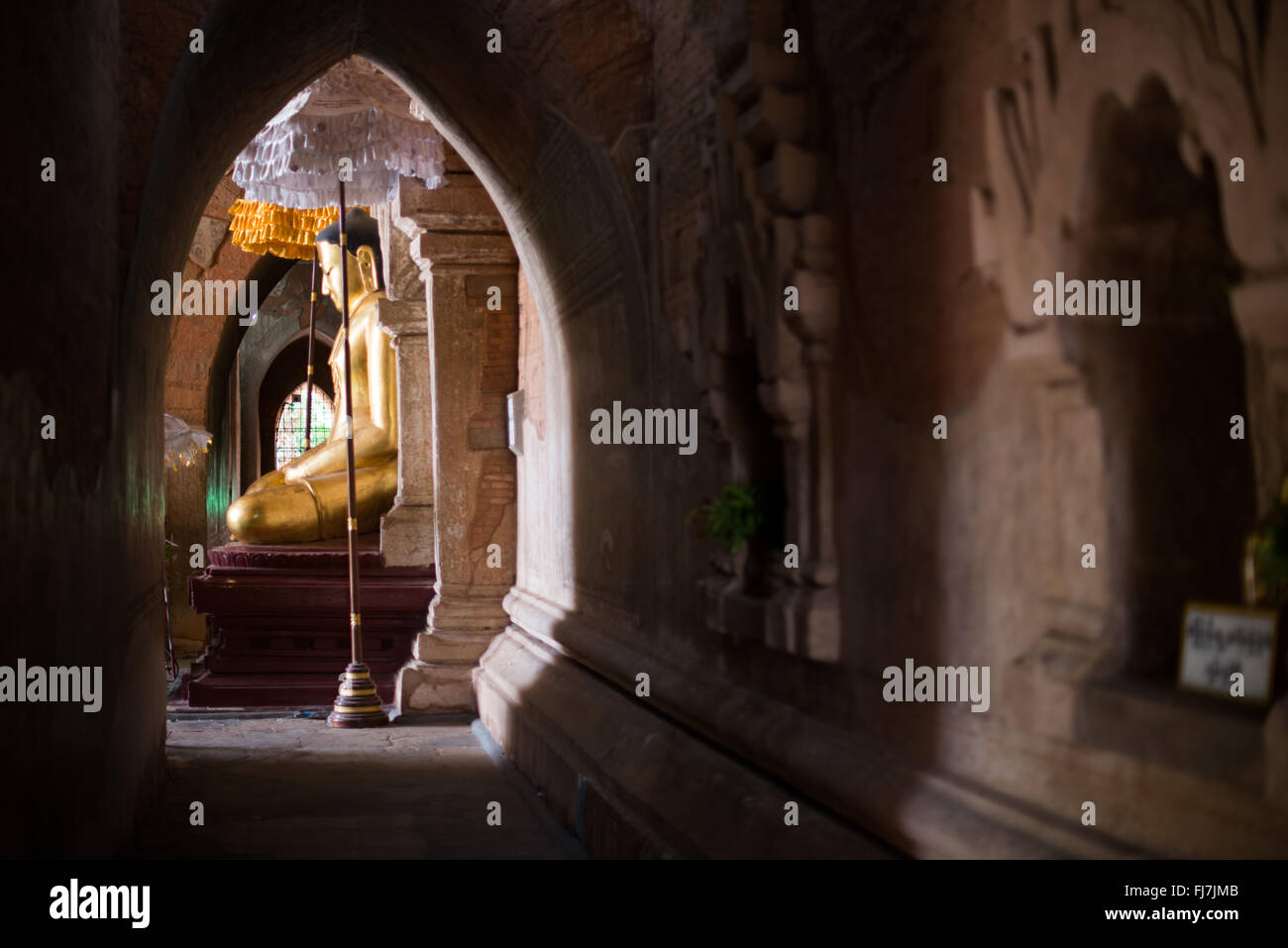 Tempio di Htilominlo statua del Buddha di Gautama Nyaung-U Myanmar // NYAUNG-U, Myanmar — Una statua d'oro del Buddha di Gautama si trova all'interno del Tempio di Htilominlo, uno dei più importanti templi buddisti nell'antica città di Bagan. Il tempio di Htilominlo fu costruito all'inizio del XIII secolo durante il regno di re Htilominlo e rappresenta lo stile architettonico del tardo periodo Bagan. Il tempio è noto per i suoi affreschi ben conservati e le molteplici immagini di Buddha ospitate all'interno delle sue camere interne. Nyaung-U funge da città di accesso alla zona archeologica di Bagan, che contiene migliaia di templi buddisti, pa Foto Stock