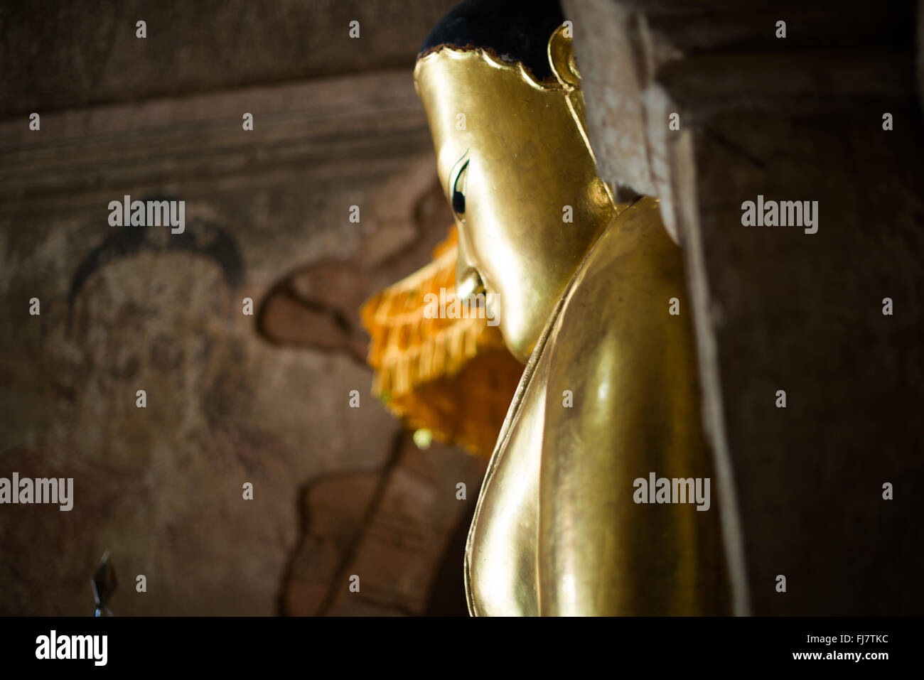 Tempio di Htilominlo statua del Buddha di Gautama Nyaung-U Myanmar // NYAUNG-U, Myanmar — Una statua d'oro del Buddha di Gautama si trova all'interno del Tempio di Htilominlo, uno dei più importanti templi buddisti nell'antica città di Bagan. Il tempio di Htilominlo fu costruito all'inizio del XIII secolo durante il regno di re Htilominlo e rappresenta lo stile architettonico del tardo periodo Bagan. Il tempio è noto per i suoi affreschi ben conservati e le molteplici immagini di Buddha ospitate all'interno delle sue camere interne. Nyaung-U funge da città di accesso alla zona archeologica di Bagan, che contiene migliaia di templi buddisti, pa Foto Stock