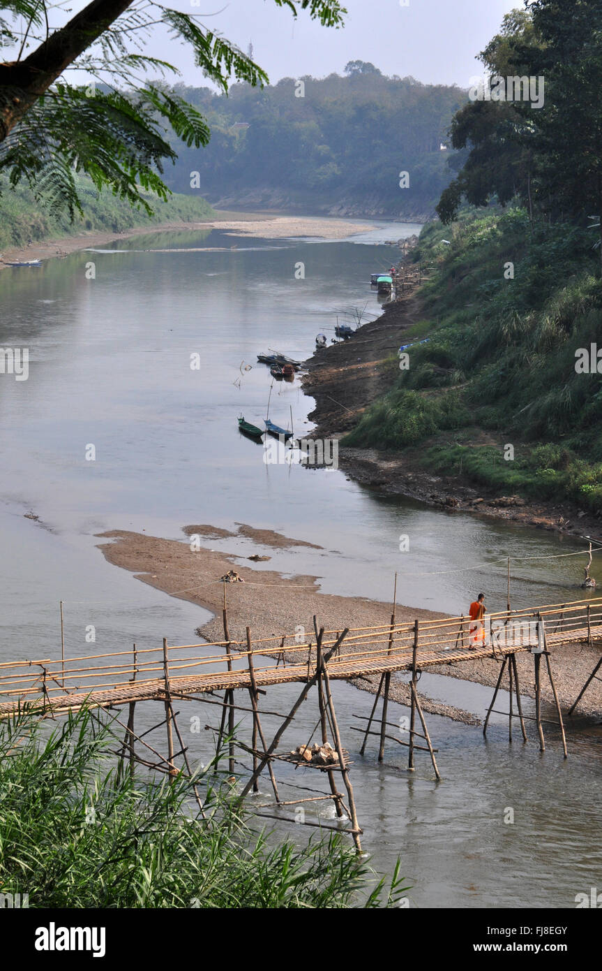 Monaco buddista attraversando un ponte di bambù, Nam Kham fiume, a Luang Prabang, Laos Foto Stock