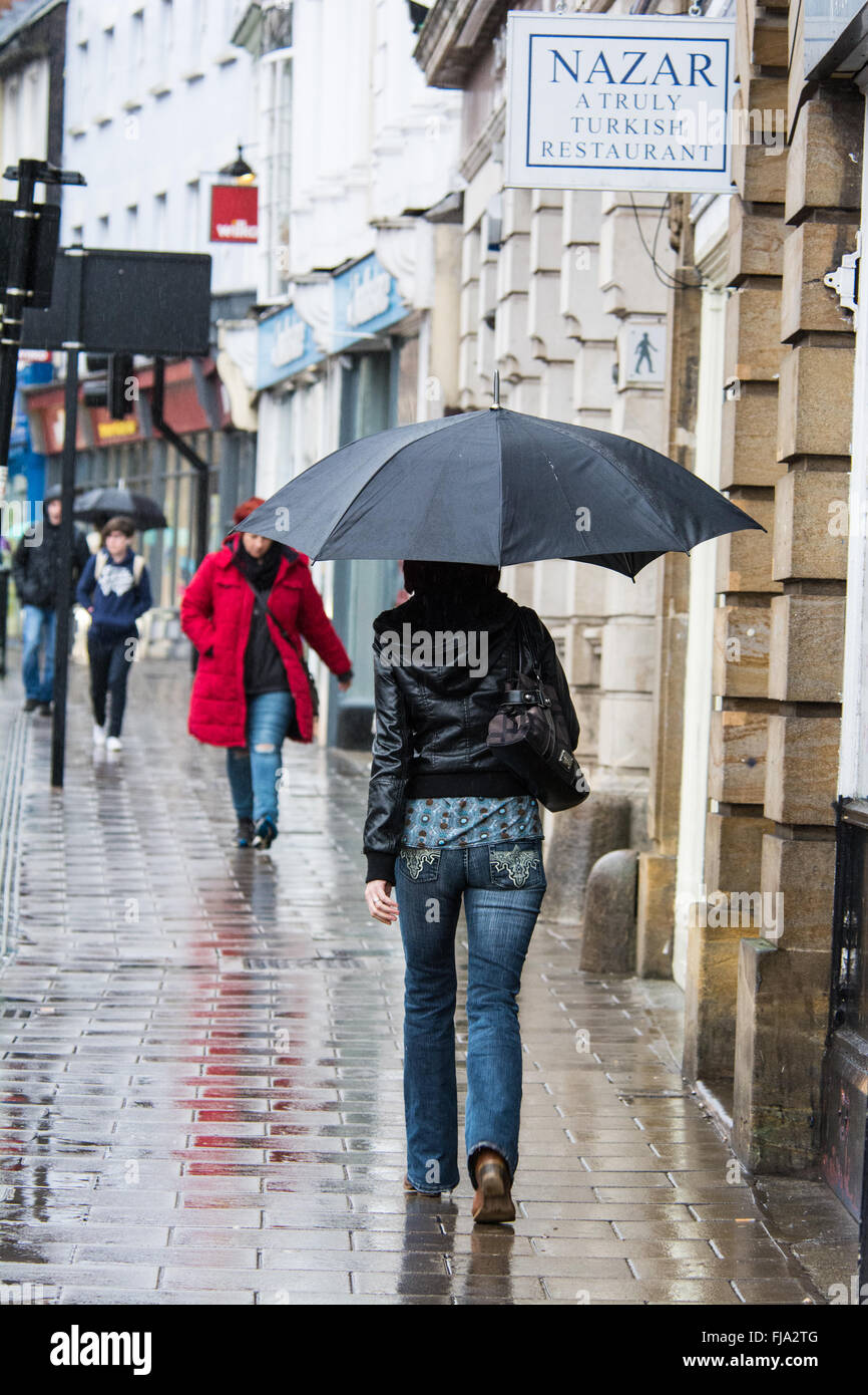 Ragazza con ombrello a camminare su high street sotto la pioggia, Bedford, Bedfordshire Foto Stock