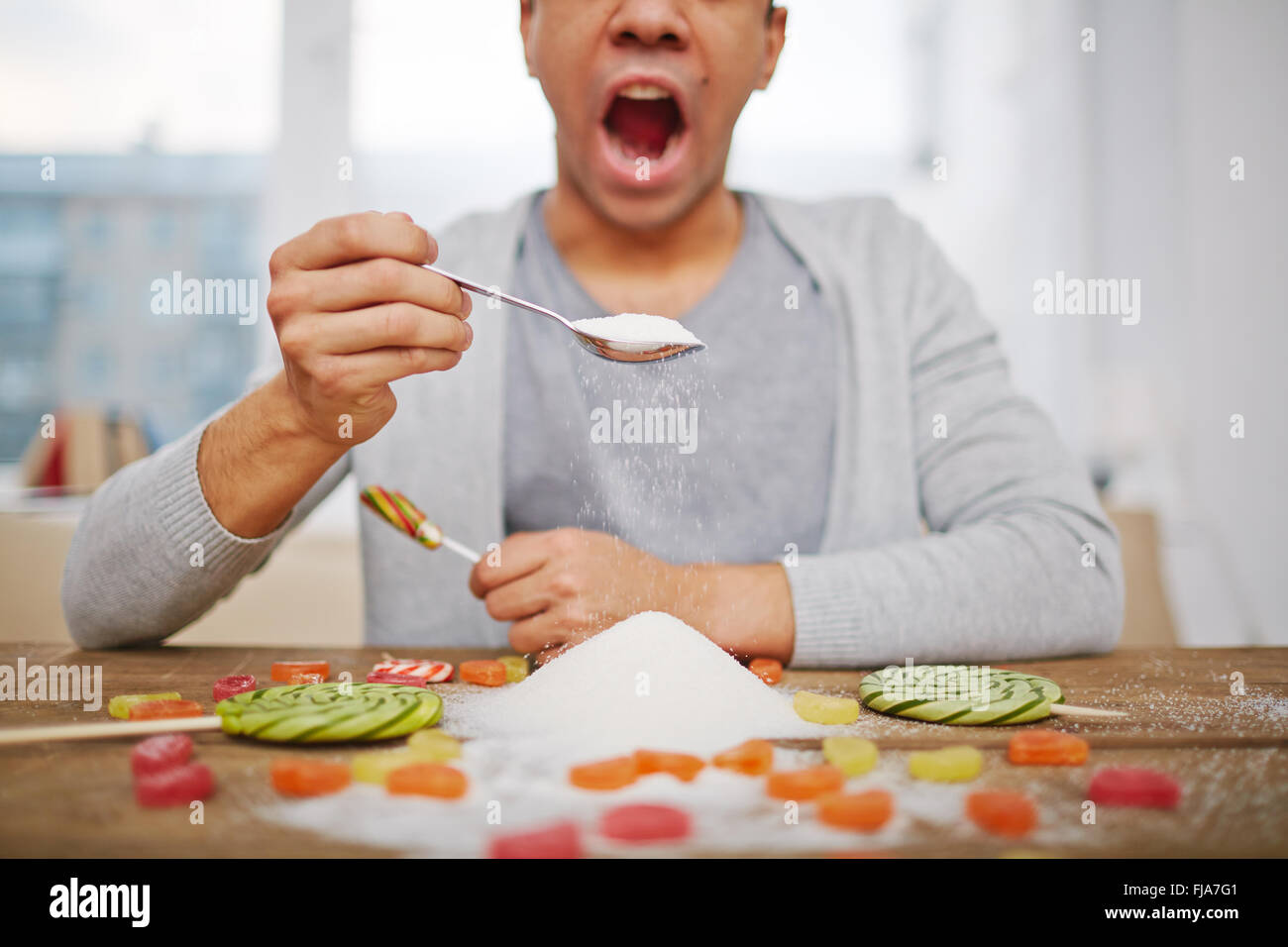 Ragazzo con cucchiaio pieno di zucchero e lecca-lecca Foto Stock