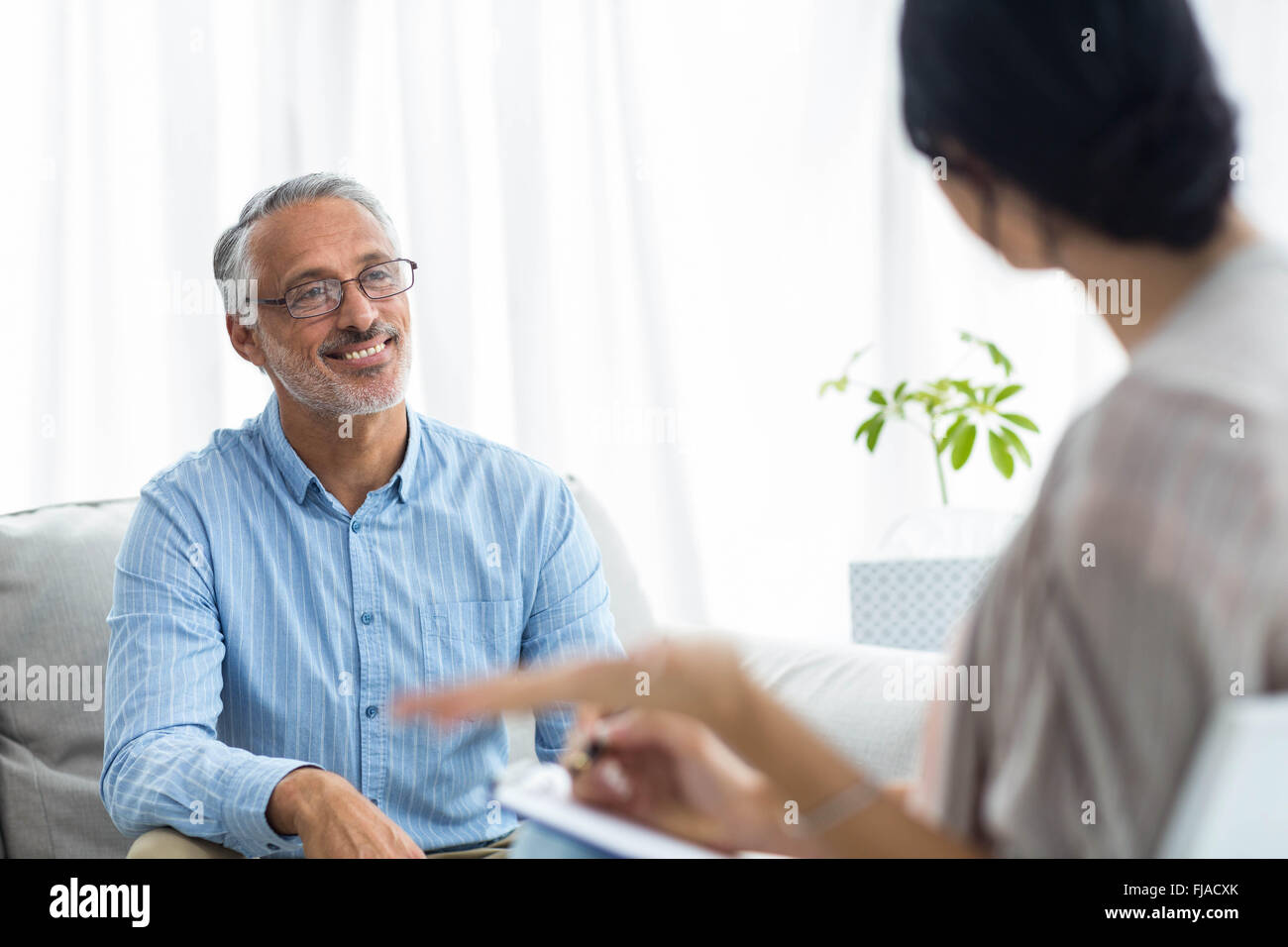 Medico donna sulla scrittura di appunti durante la consultazione di un uomo Foto Stock