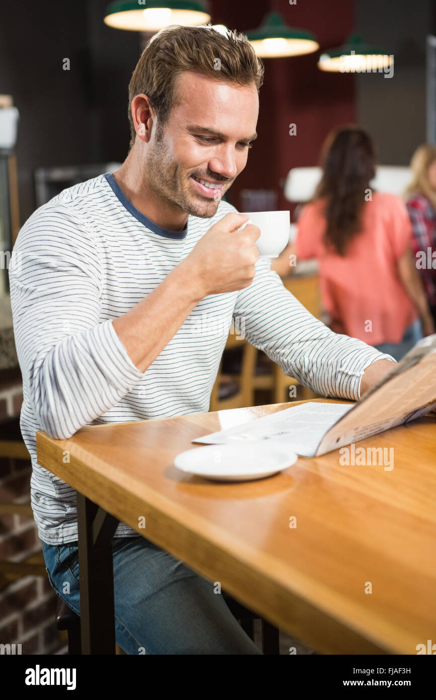 Uomo bello leggere il giornale e avente un caffè Foto Stock