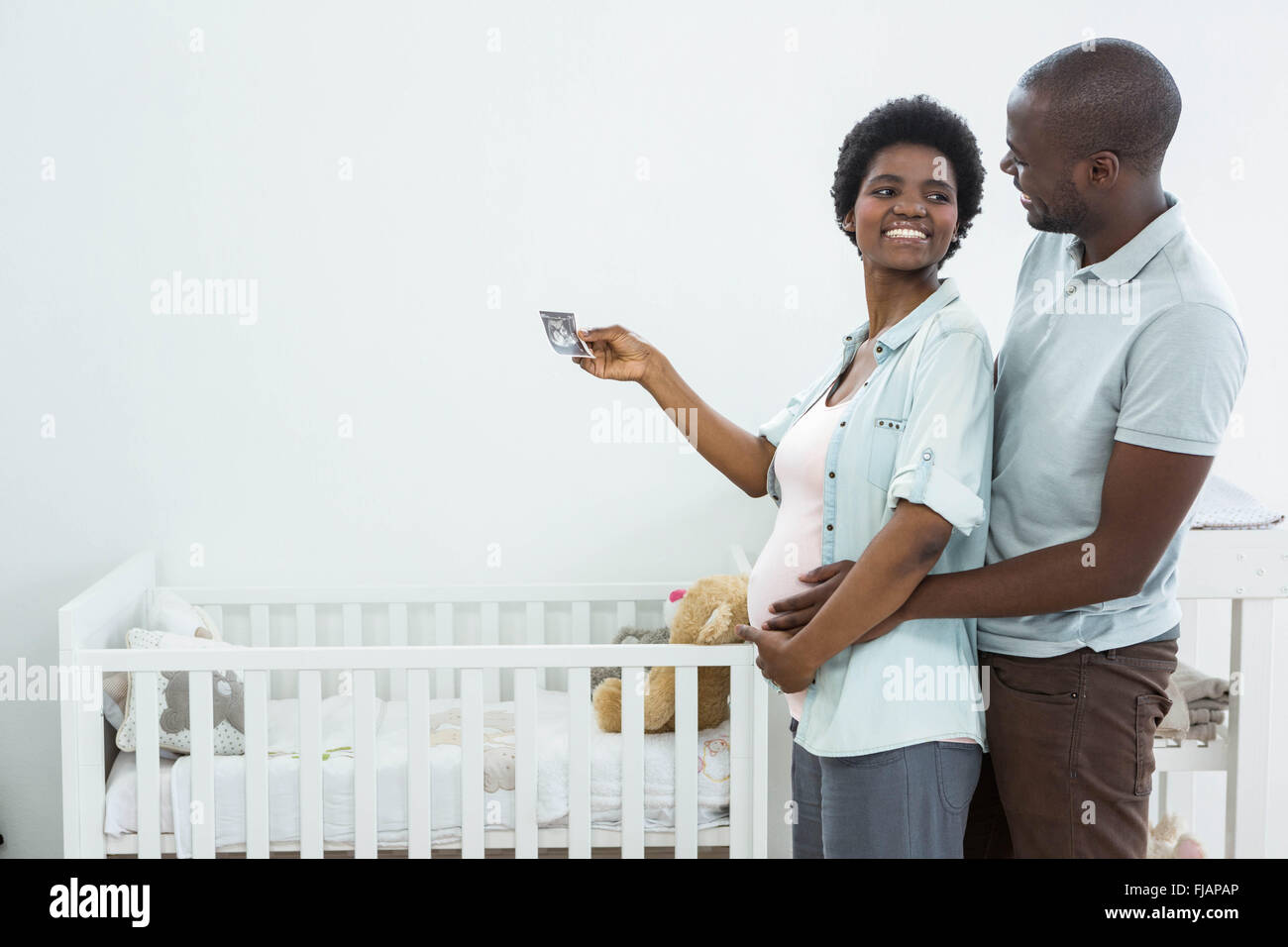 Incinta giovane azienda di scansione ad ultrasuoni vicino a culla baby Foto Stock