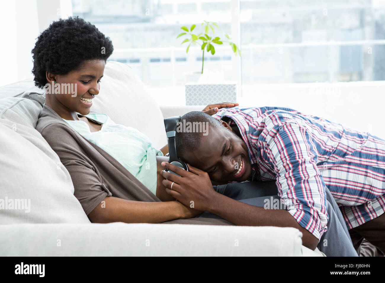 Uomo con le cuffie sulla gravidanza womans stomaco Foto Stock