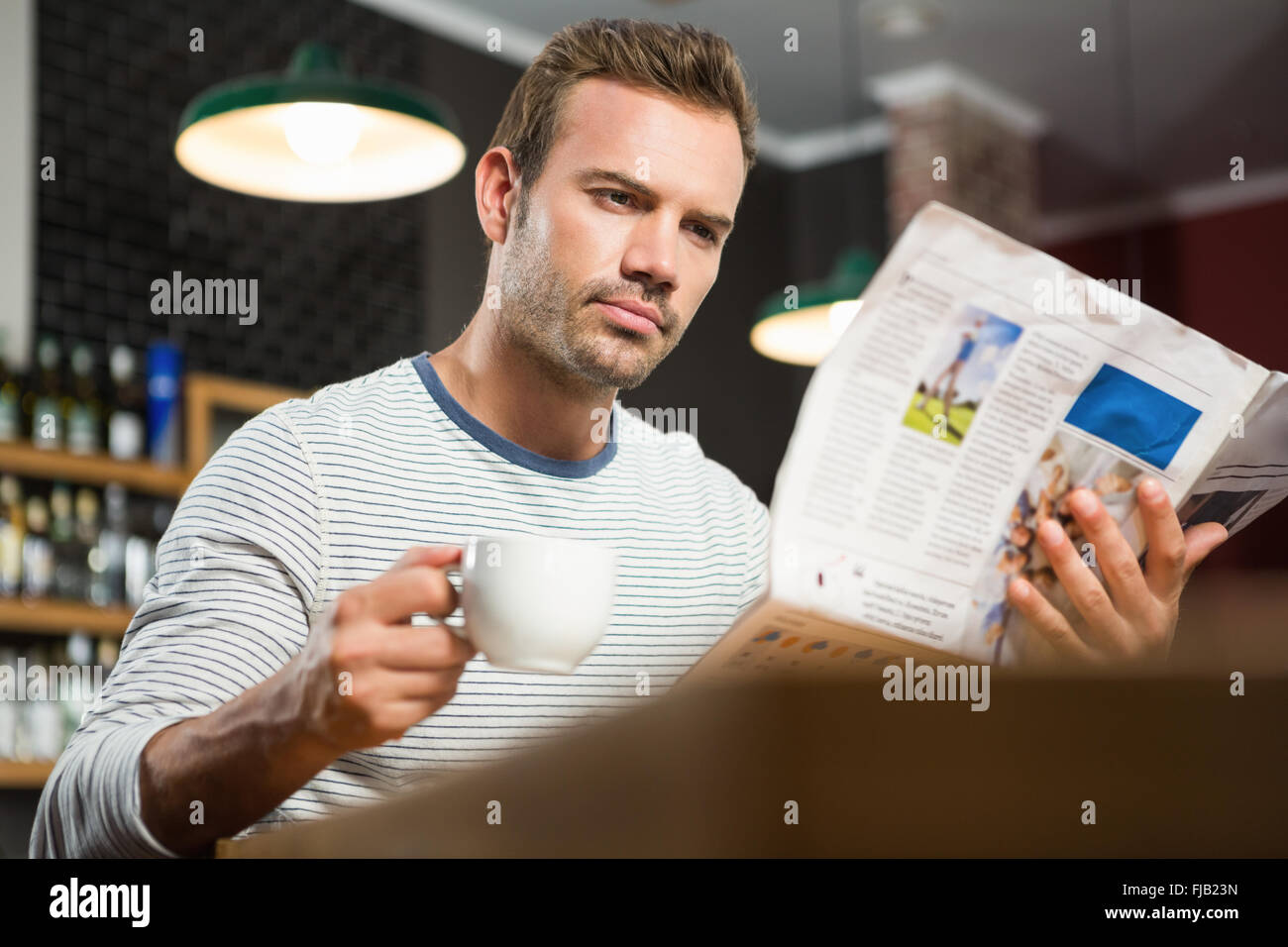 Uomo bello leggere il giornale e avente un caffè Foto Stock