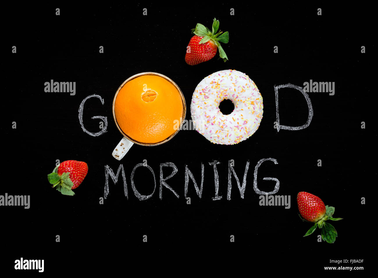 Buona mattina saluto scritto su gesso nero bordo. Ciambella (ciambella), arancio dolce e fragole. Concetto di colazione Foto Stock