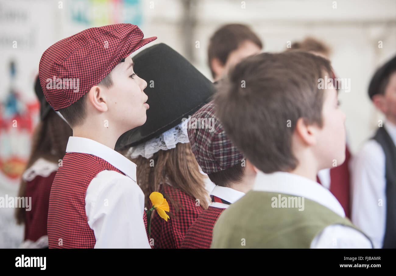 Carmarthen, Galles, Regno Unito. 1st marzo 2016. Carmarthen, Galles, Regno Unito. 1st marzo 2016. Ragazzo, ragazzi, ragazza, ragazze, Bambini, bambini, alunni, studenti, dalla scuola di Nantgaredig in costume nazionale del Galles cantare canzoni in gallese a Guildhall Square, Carmarthen, Carmarthenshire, Galles, Regno Unito. Credit: Paul Quayle/Alamy Live News Foto Stock