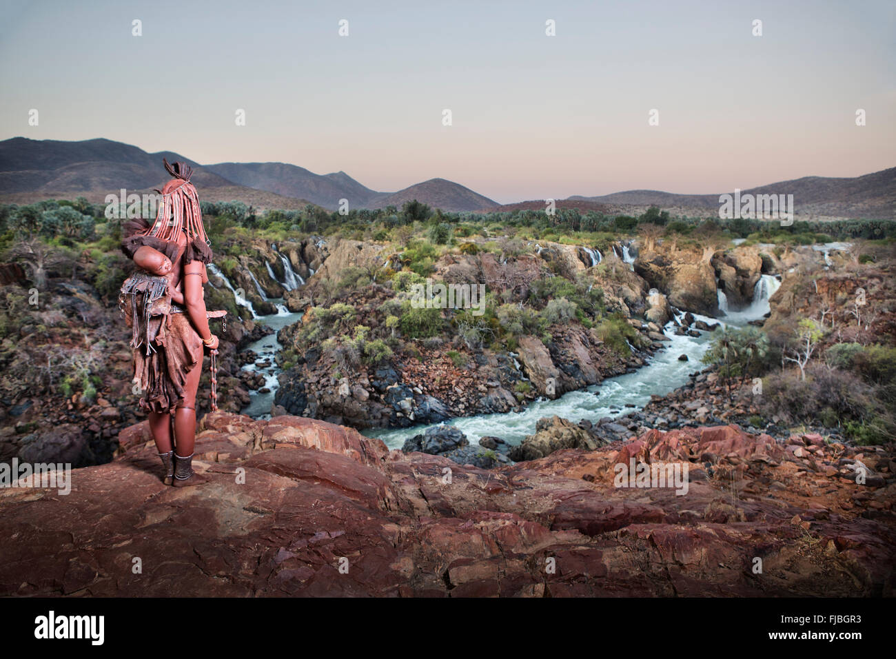 Donna Himba affacciato Epupa Falls. Foto Stock