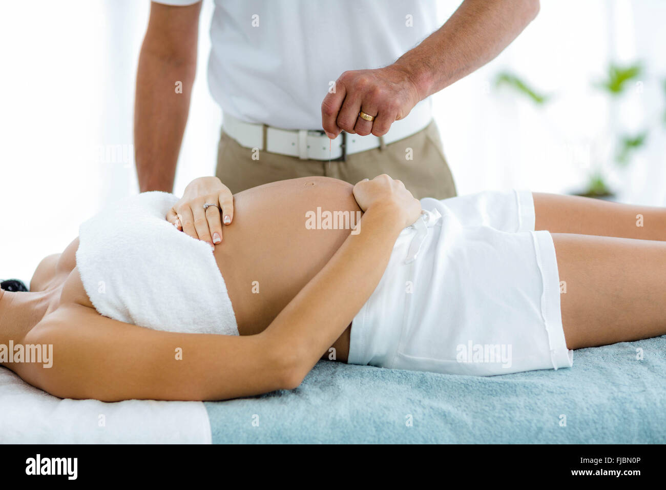 Donna incinta riceve un trattamento spa dal massaggiatore Foto Stock