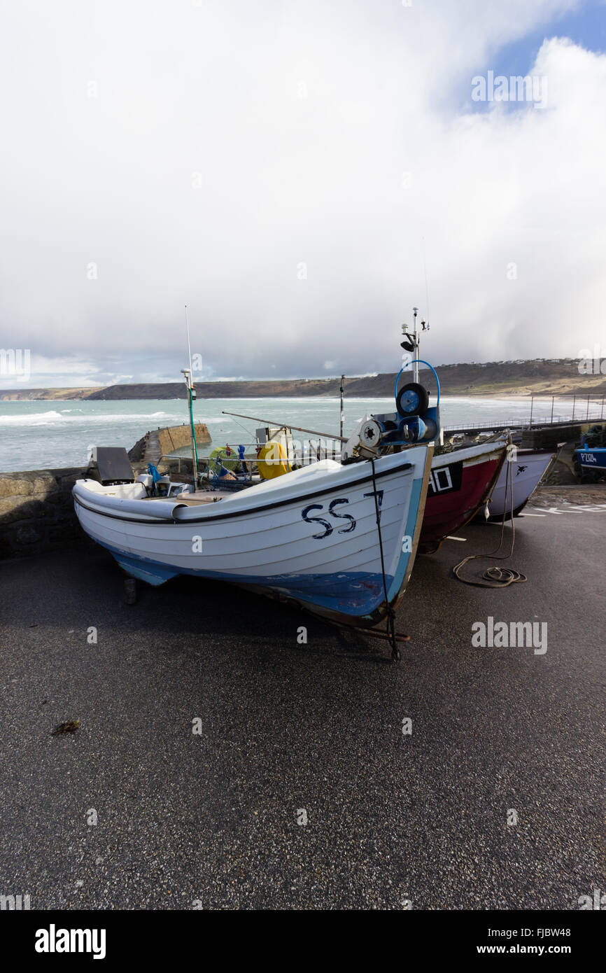 Onshore barche da pesca trainata dal porto di Sennen Cove, Cornwall, Regno Unito sotto tempestoso cielo invernale Foto Stock