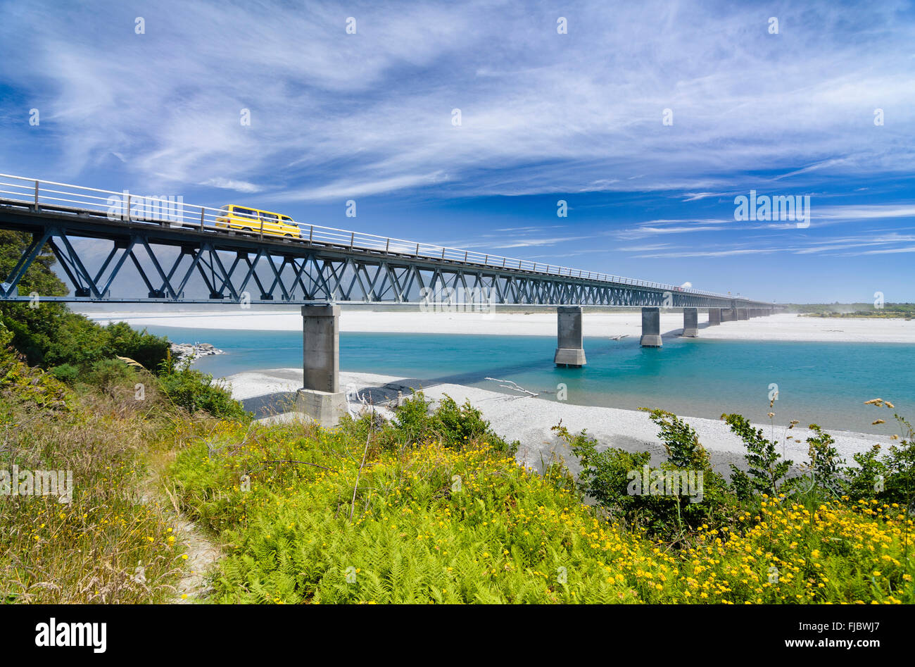Giallo auto guida su Haast River Bridge e il più lungo di una singola corsia ponte in Nuova Zelanda, nella costa occidentale dell'Isola del Sud, Nuova Zelanda Foto Stock