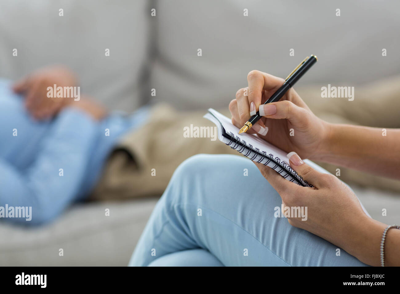 Medico donna iscritto su notepad durante la consultazione di un uomo Foto Stock