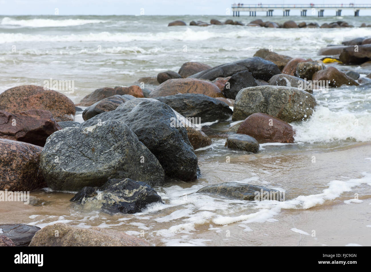 Pietre giacciono in un mare infuria sotto colpi di grandi onde Foto Stock