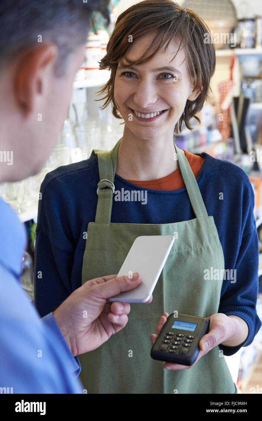 Uomo che utilizza il pagamento senza contatto App sul telefono cellulare in negozio Foto Stock