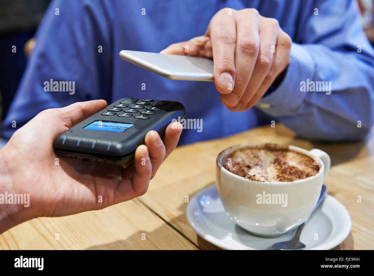 Uomo che utilizza il pagamento senza contatto App sul telefono cellulare in Cafe Foto Stock