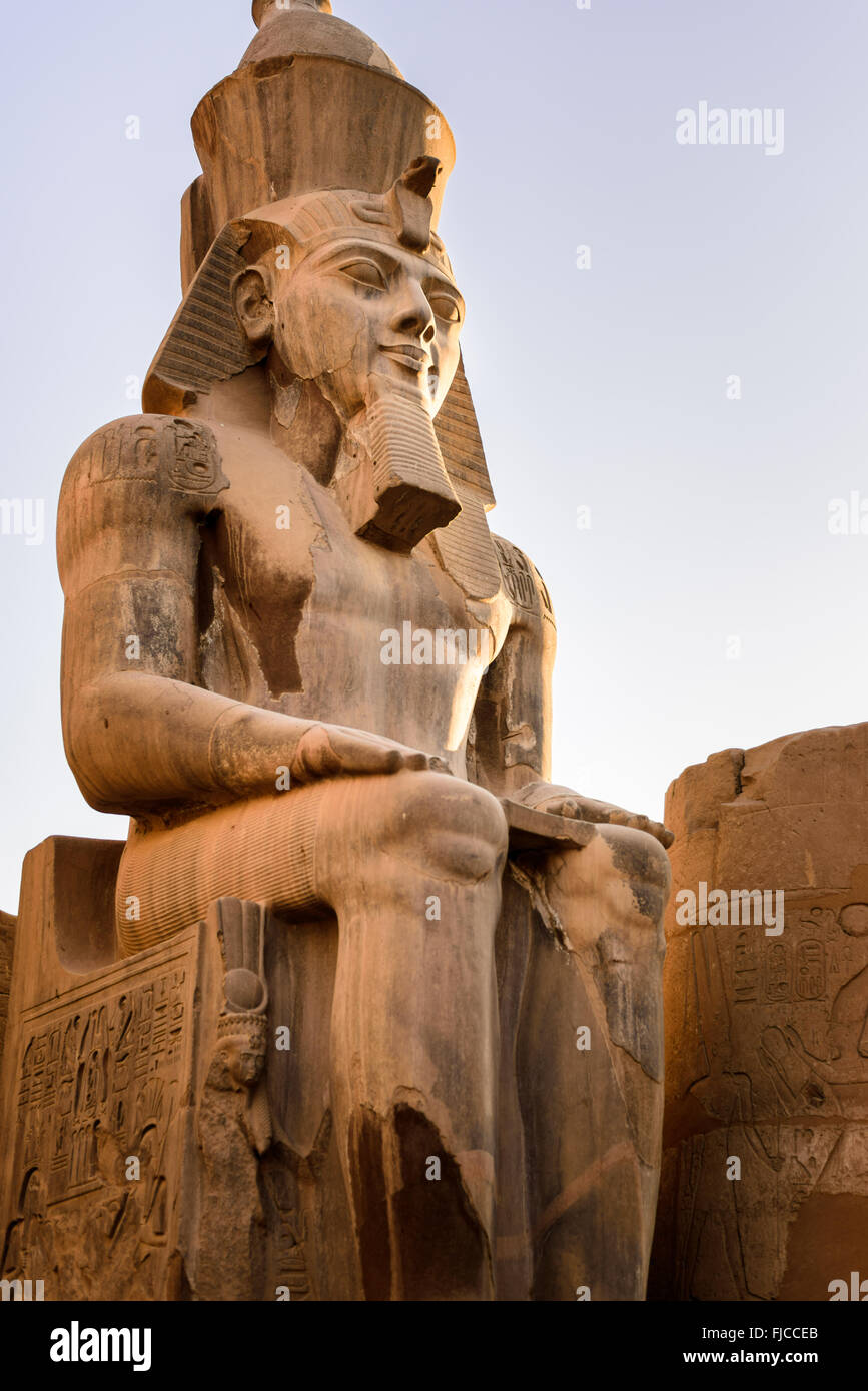 Statua di Ramessess II seduto di fronte a una delle porte del tempio di Luxor. Foto Stock