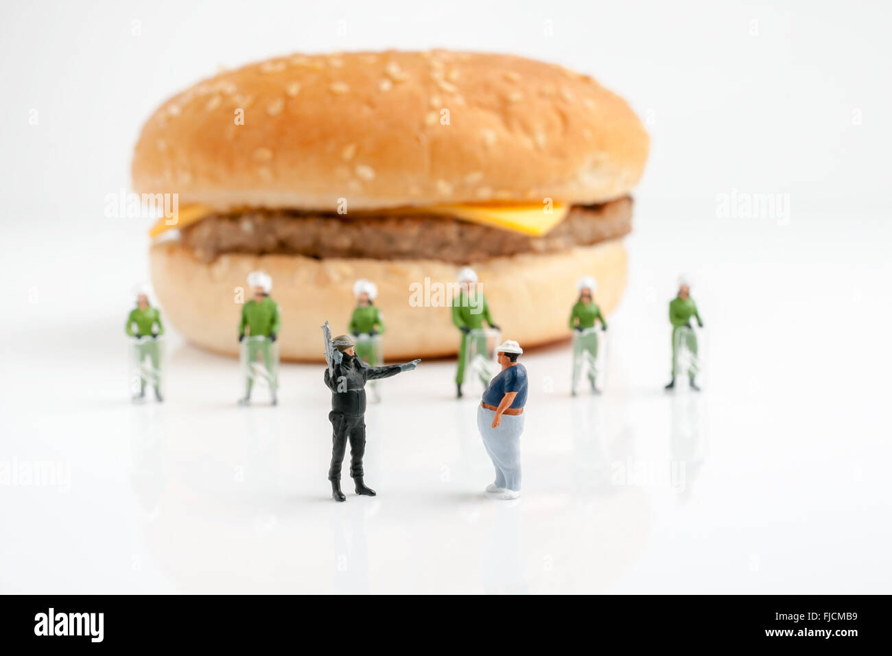 Tiny polizia impedendo un uomo sovrappeso dal raggiungimento di un burger una sanità pubblica il concetto di obesità Foto Stock