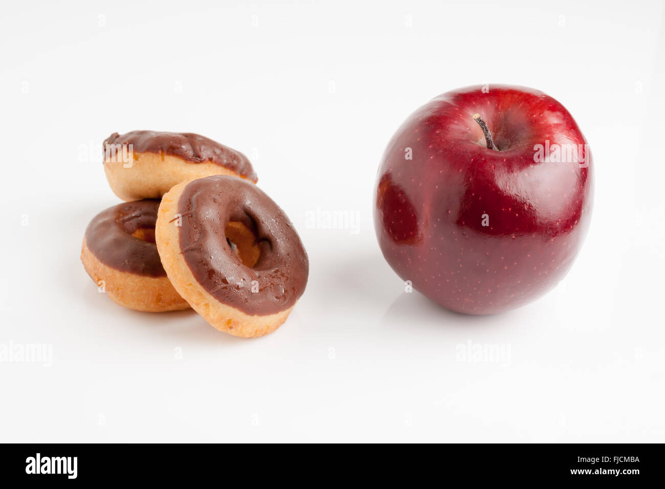 Ciambelle al cioccolato o una bella sana rosso lucido apple una dieta o junk food concept Foto Stock