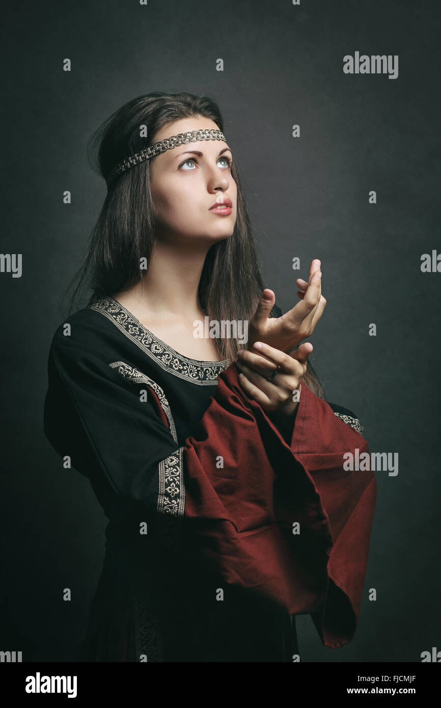 Bella donna in abiti medievali pregando con gli occhi al cielo. Storico e religione Foto Stock