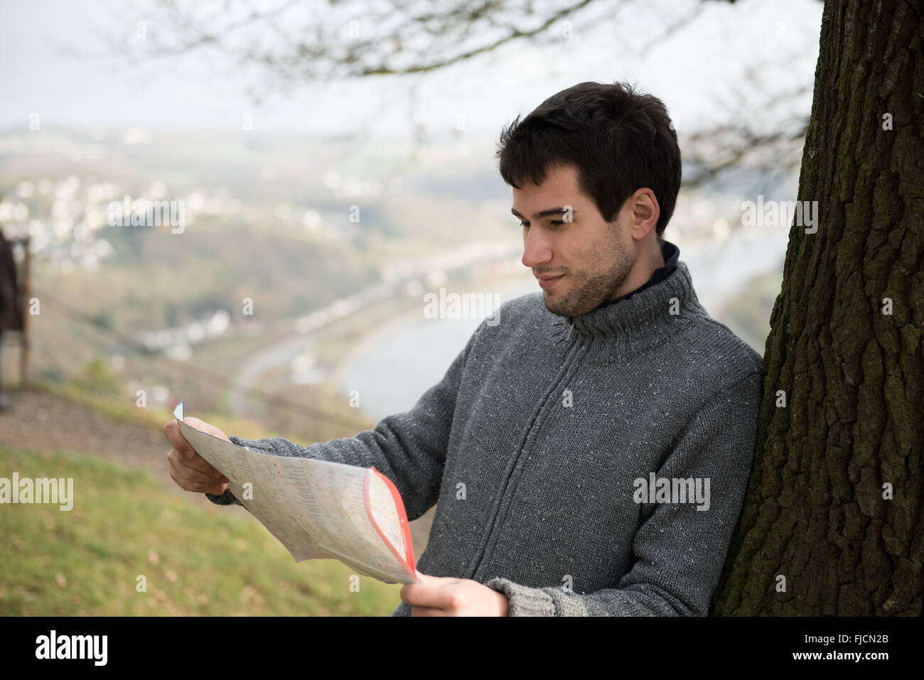 Giovane uomo di fronte a Rheine river, Germania, usando la mappa Foto Stock