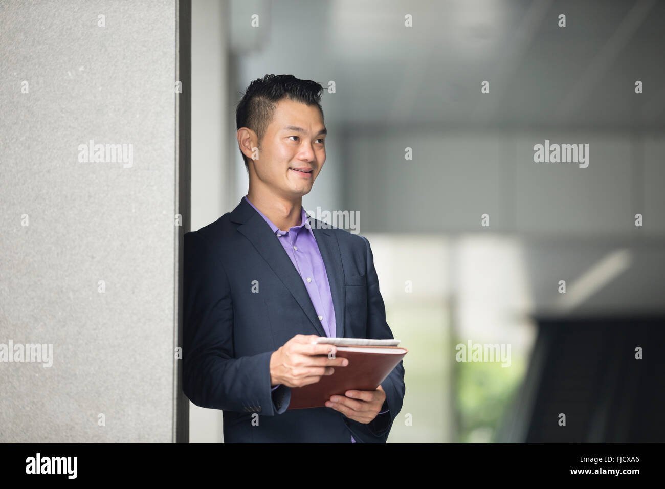 Ritratto di un felice imprenditore asiatico che guarda lontano. Chinese business man standing all'esterno. Foto Stock