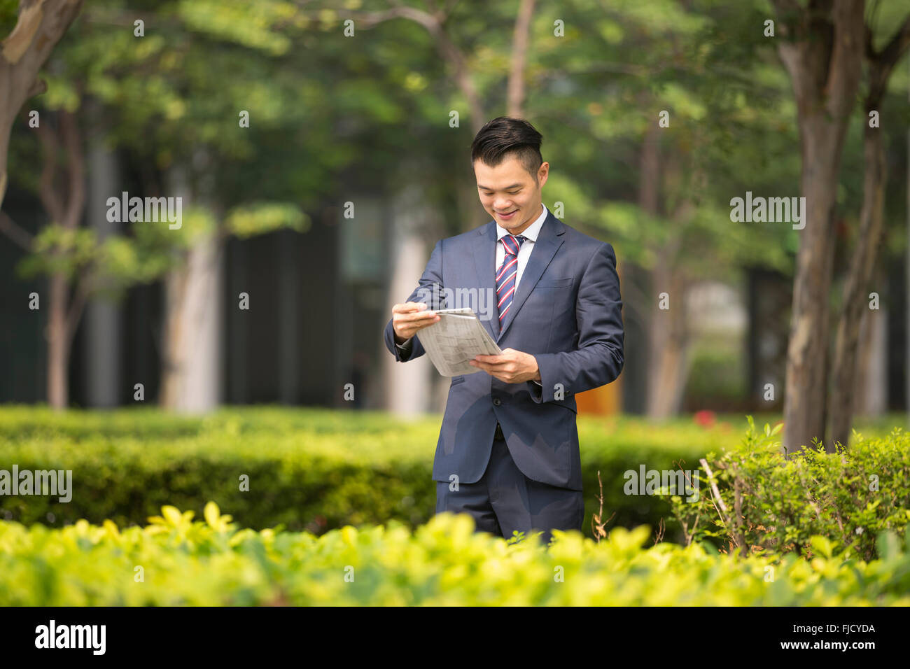 Chinese Business man al di fuori ufficio leggendo un giornale. Asian business uomo prendendo una pausa. Foto Stock