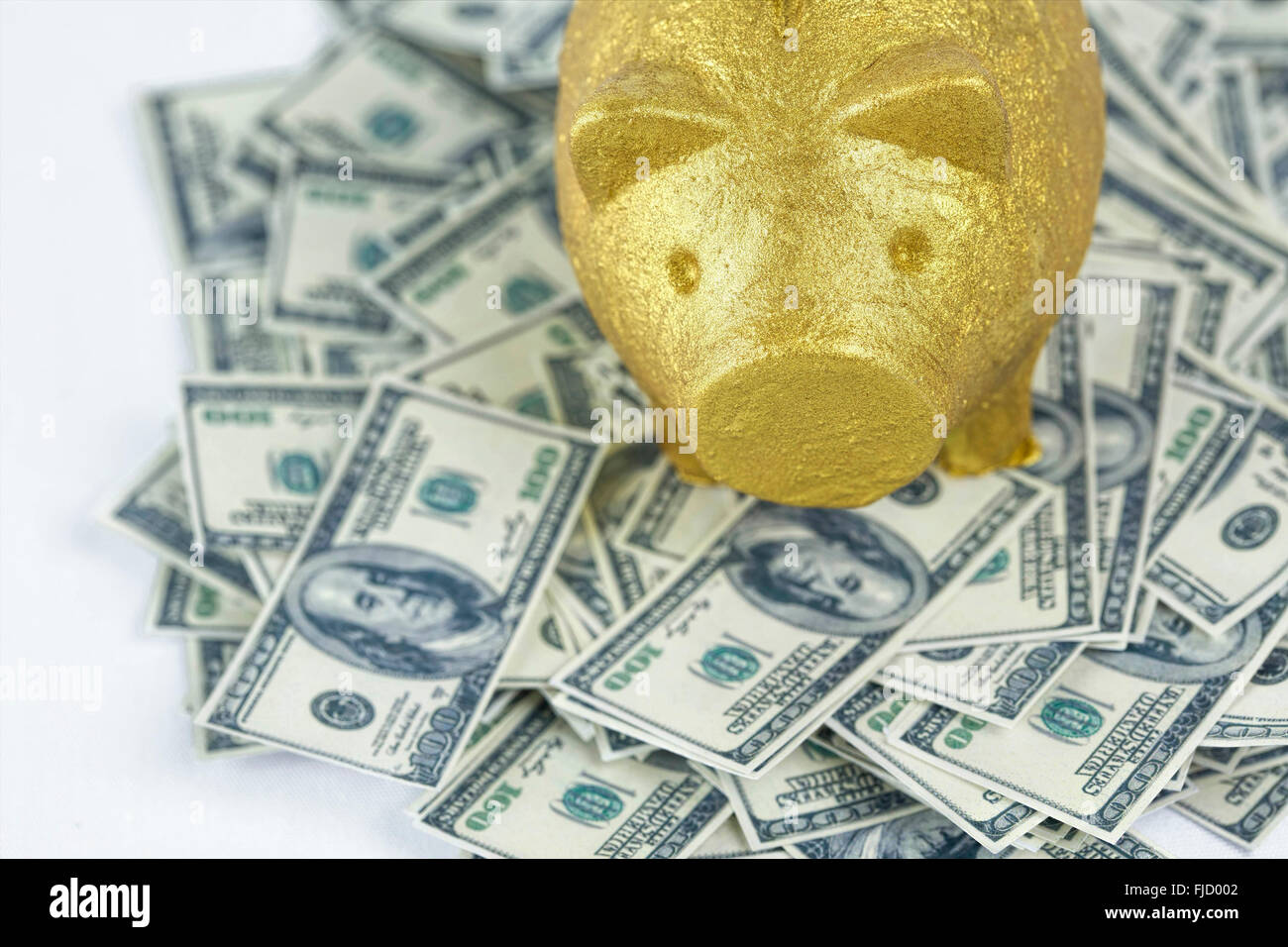 Golden salvadanaio sulla pila di note di 100 dollari Foto Stock
