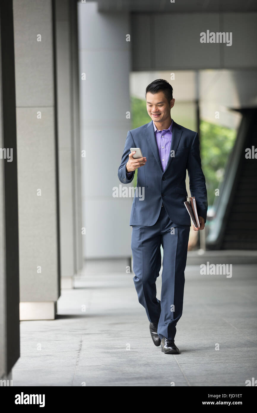 Un felice cinese uomo business utilizzando il suo smart phone. Foto Stock