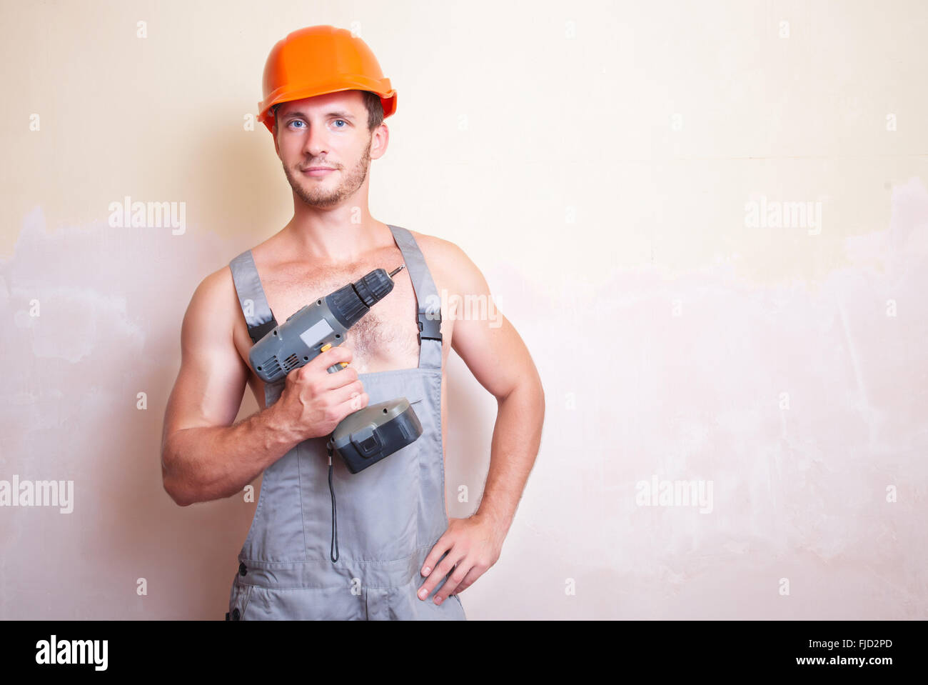 Un uomo in tuta e casco con un cacciavite Foto Stock