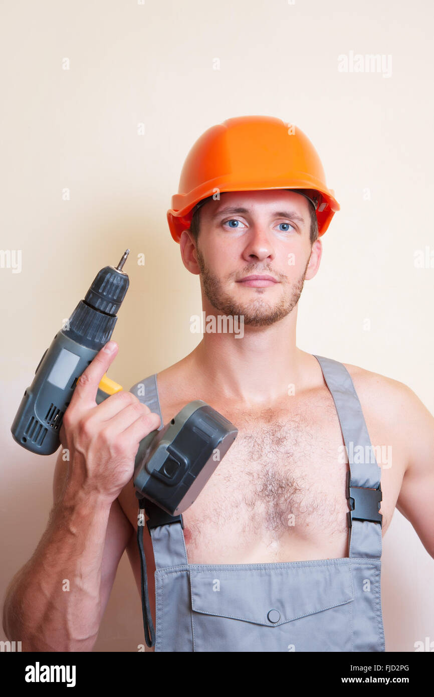 Un uomo in tuta e casco con un cacciavite Foto Stock