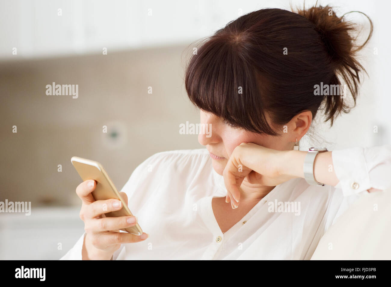 La donna nella sua casa utilizzando il telefono cellulare per comunicare con i suoi amici Foto Stock