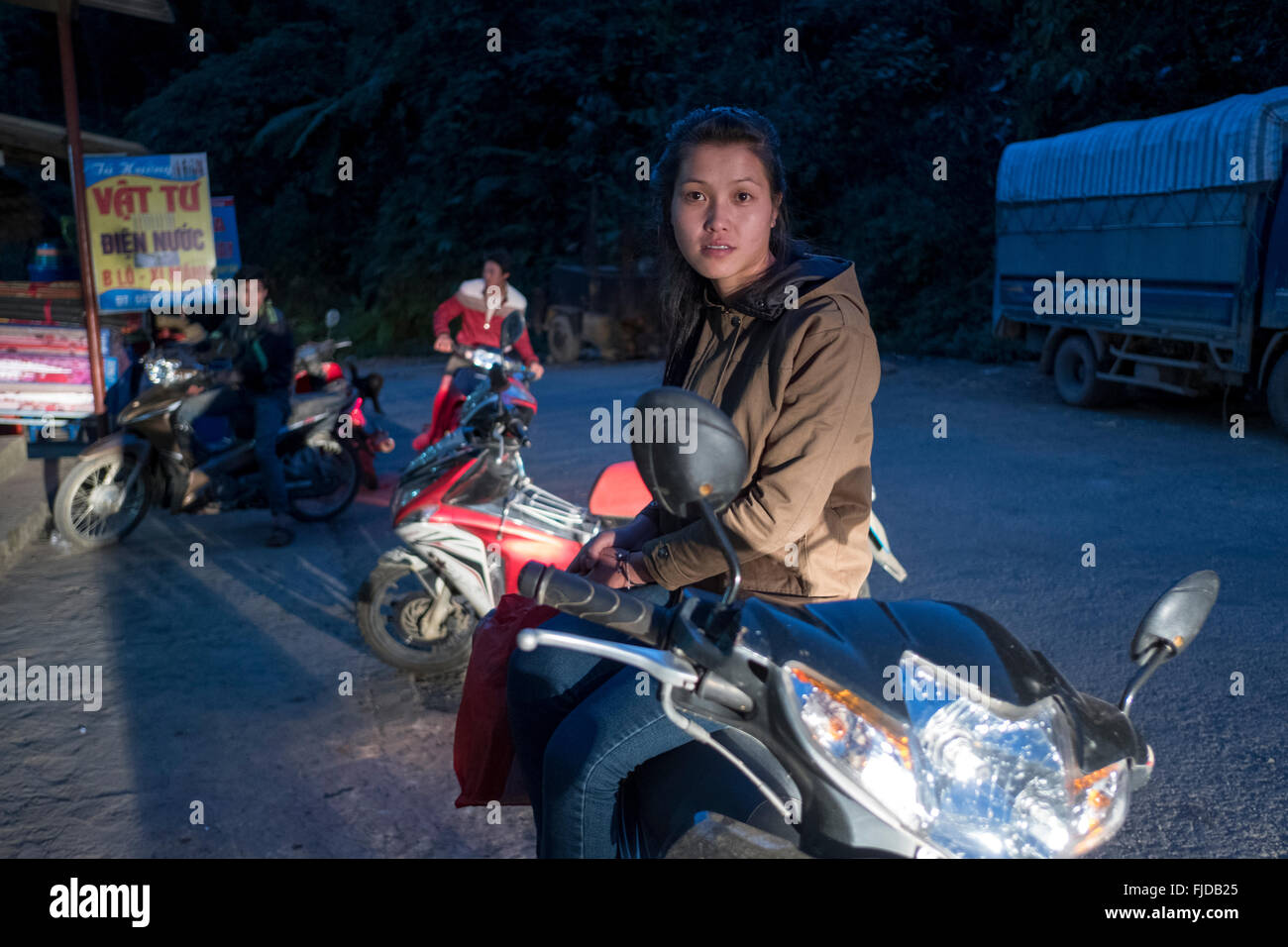 Una giovane donna riposa sulla sua moto nel villaggio di Ban Khoang nel nord del Vietnam Foto Stock
