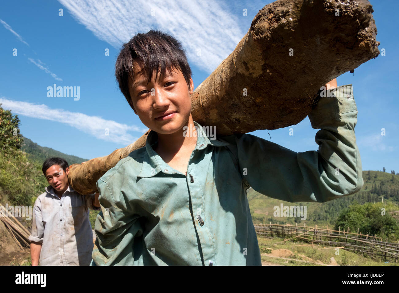 Gli uomini portano la legna attraverso il villaggio hmong di Ban Den nel distretto di Sapa, nel Vietnam del nord. Foto Stock