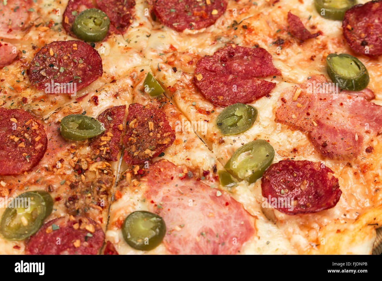 Hot pizza italiana con salsiccia per pizza, prosciutto e peperoncino jalapeno close up. Profondità di campo Foto Stock