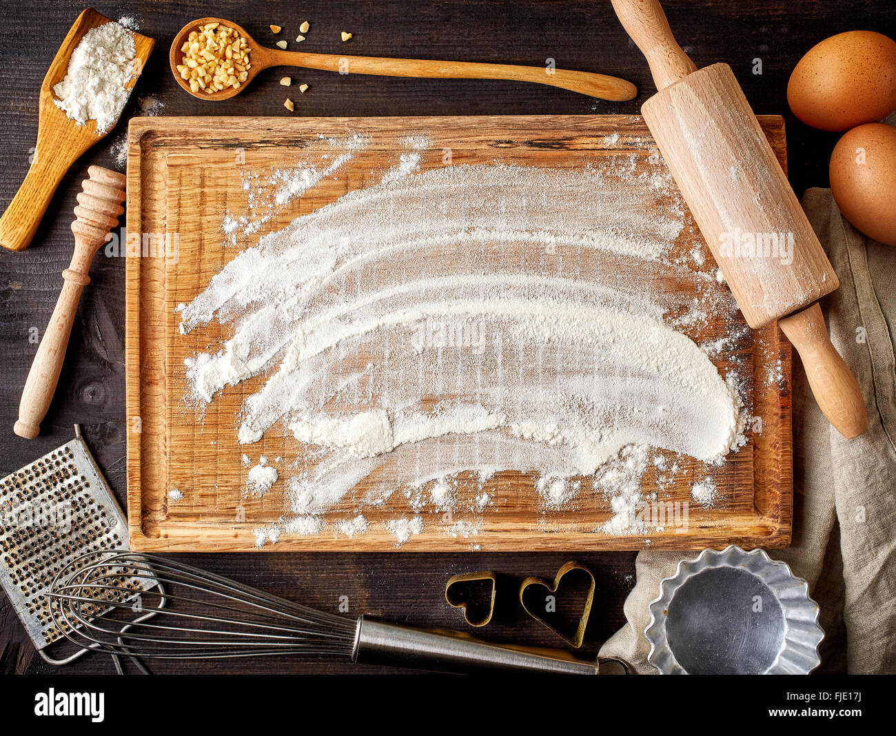 La cottura lo sfondo con il bordo di taglio, uova, zucchero, farina, mattarello, grattugia e cucchiai, vista dall'alto Foto Stock