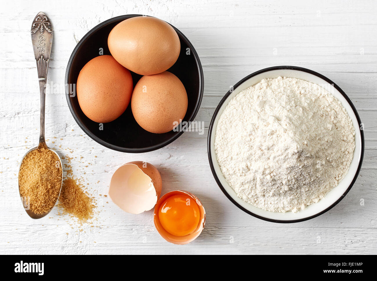 Il lievito, le uova, la farina bianca e zucchero bianco sul tavolo di legno, vista dall'alto Foto Stock