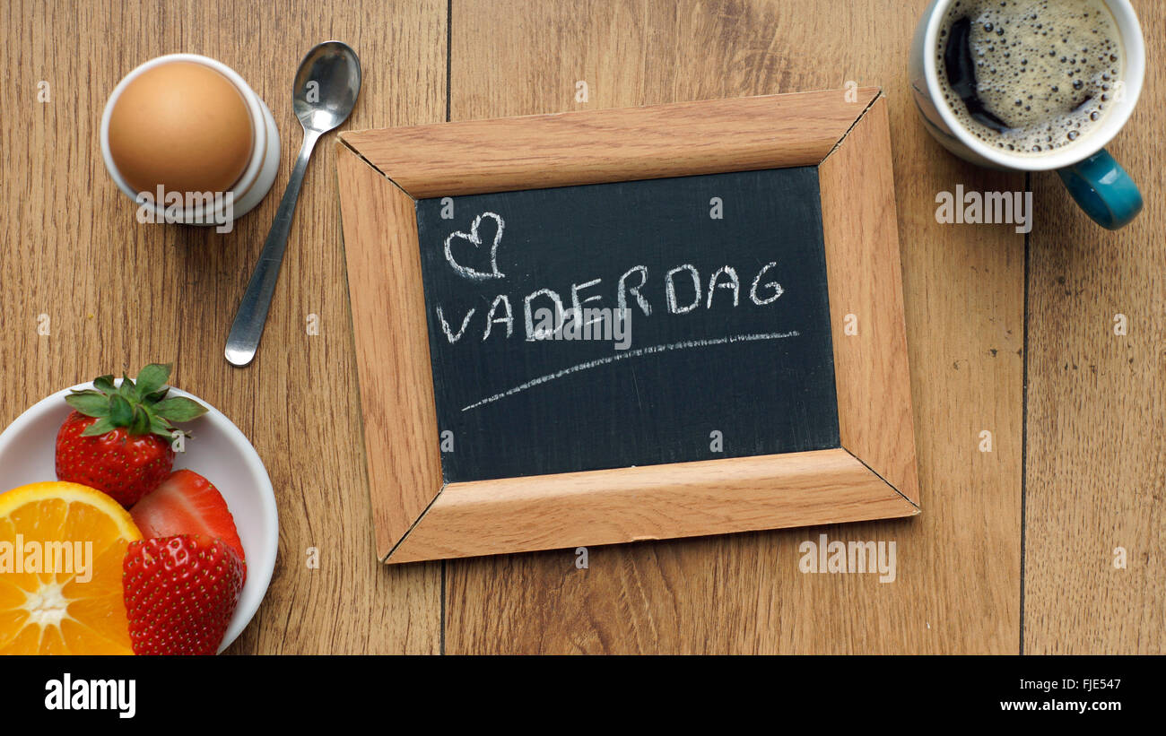 La festa del papà scritto in olandese su una lavagna tra una prima colazione per lui Foto Stock