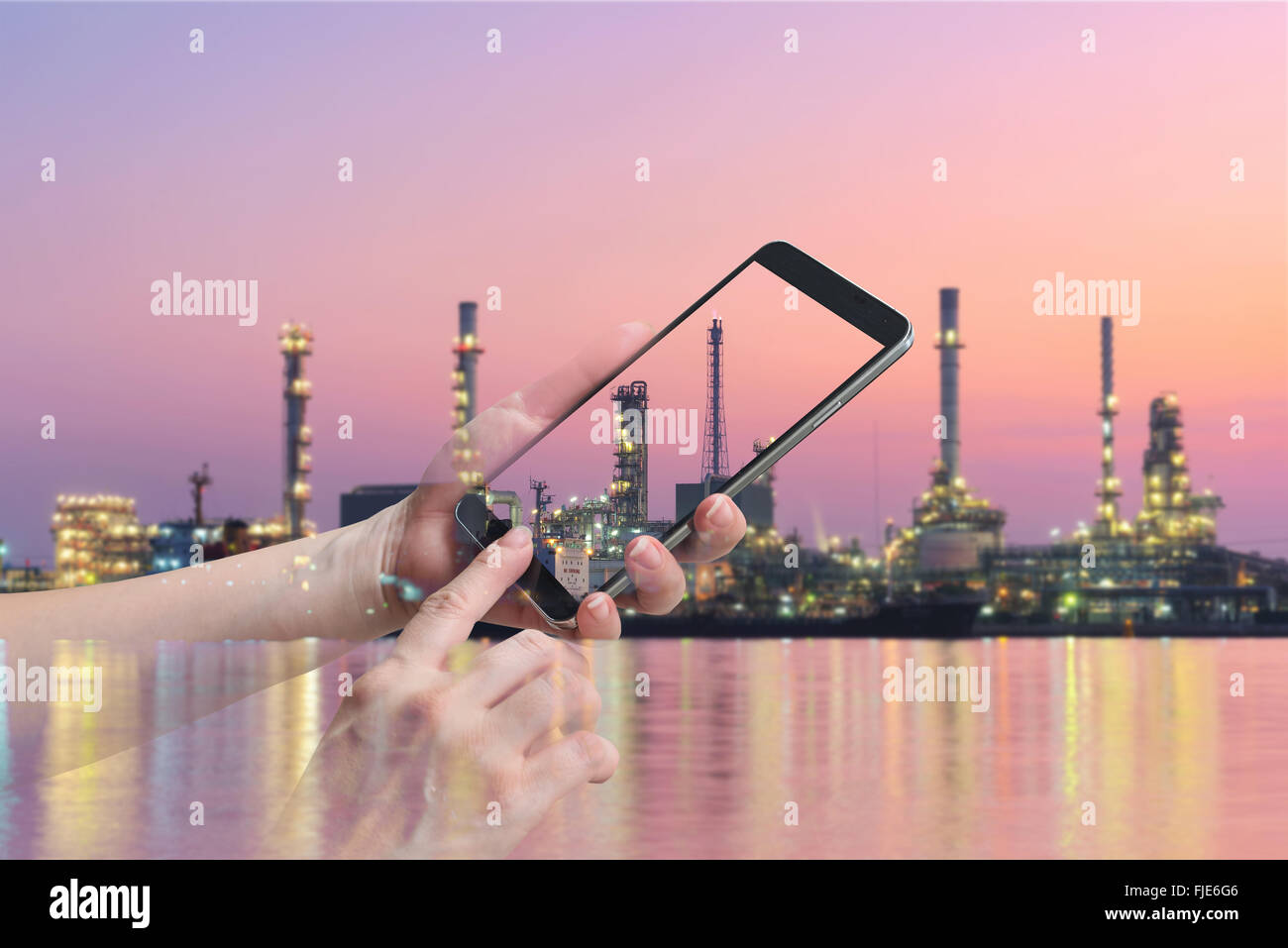 La doppia esposizione femminile di tenere in mano e il touch screen smart phone, sulla raffineria di petrolio sfondo sfocato. Foto Stock