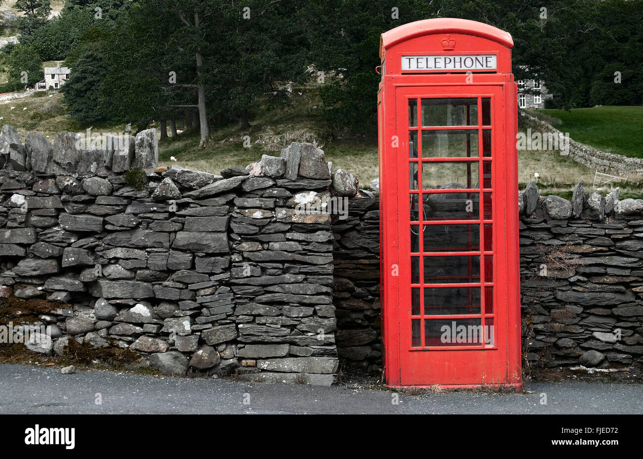 Un telefono rosso scatola da un secco rurale muro di pietra in Cumbria Foto Stock