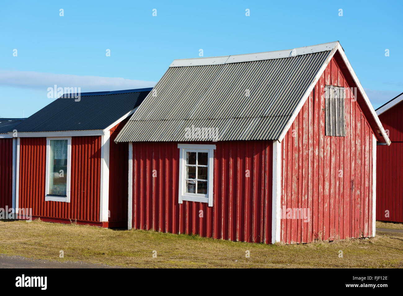 Un piccolo rosso e pesca in legno o tool shed con facciata a spiovente e tetto in acciaio. Foto Stock