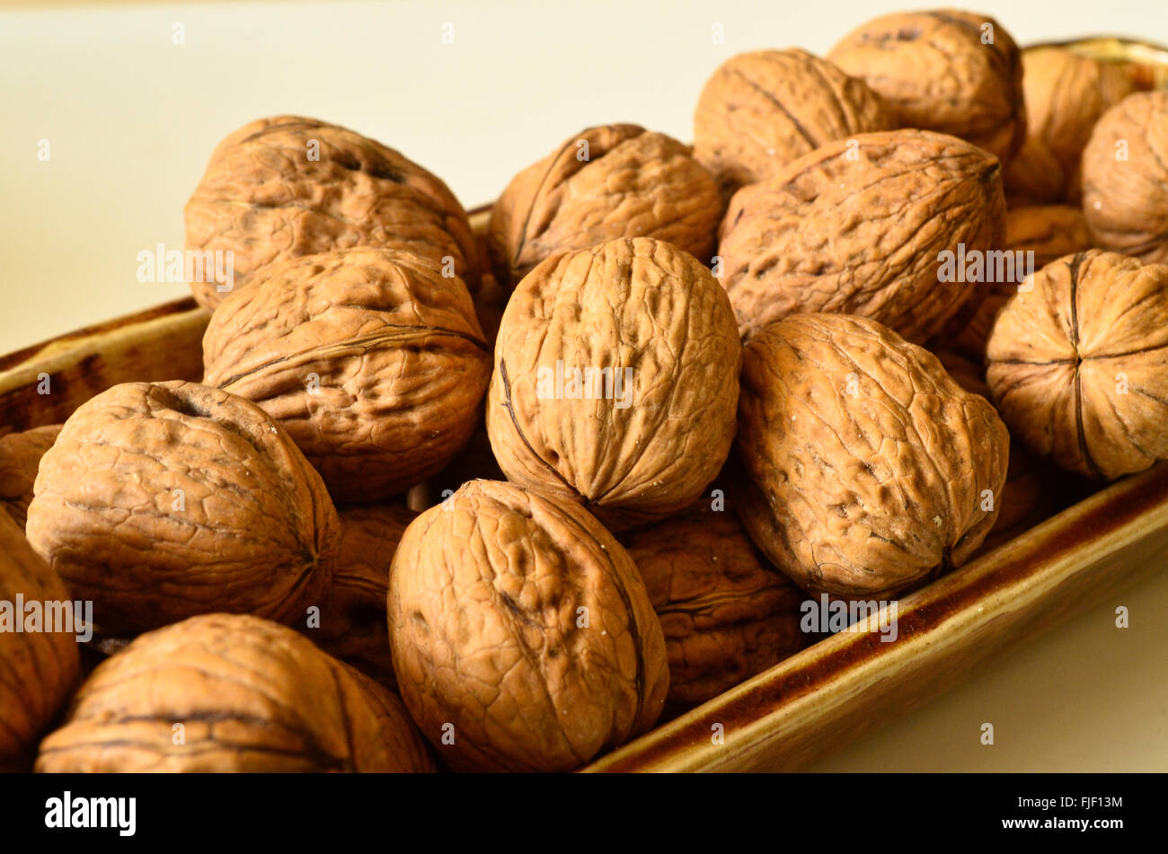 Noci comuni con guscio in un contenitore di porcellana. Foto Stock