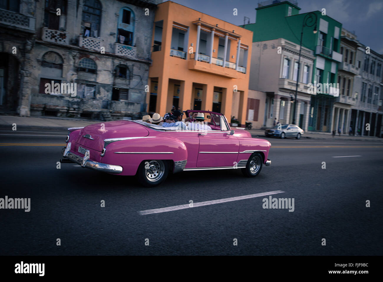L'Avana, Cuba. Un auto d'epoca passeggiate lungo Malecòn, il lungomare della città, al tramonto. Foto Stock