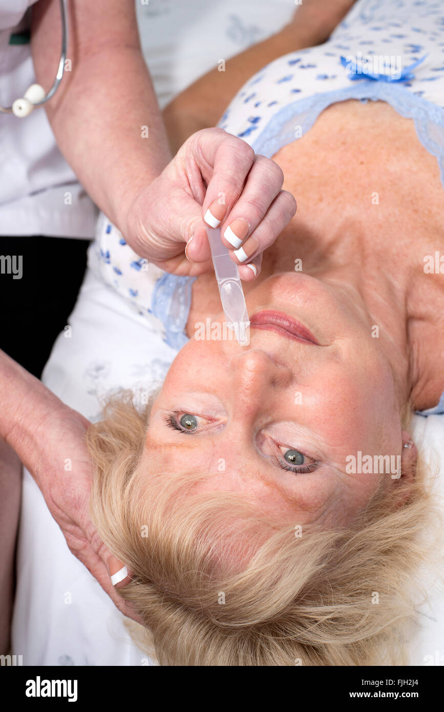 L'infermiera la somministrazione di gocce nasali in pazienti con un naso Foto Stock
